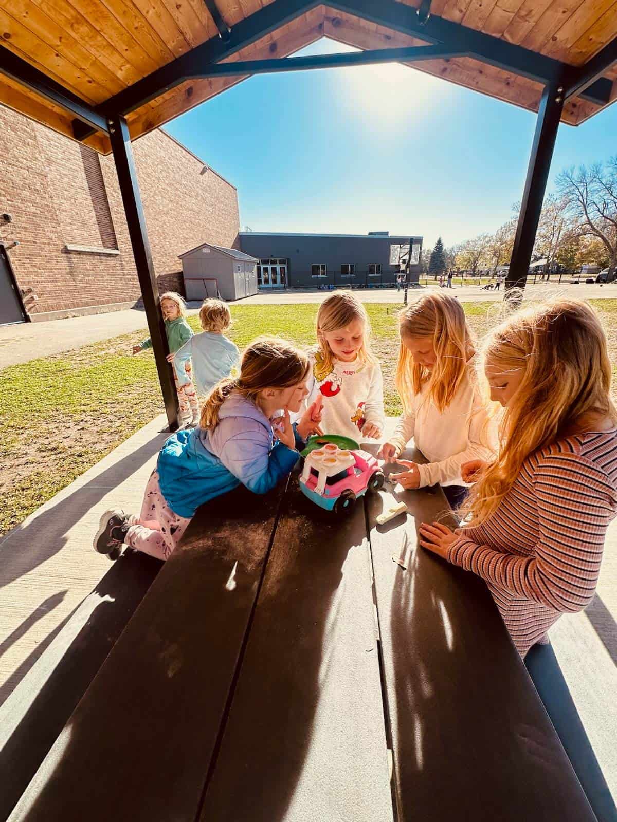 girls playing at an outside picnic table on a sunny day