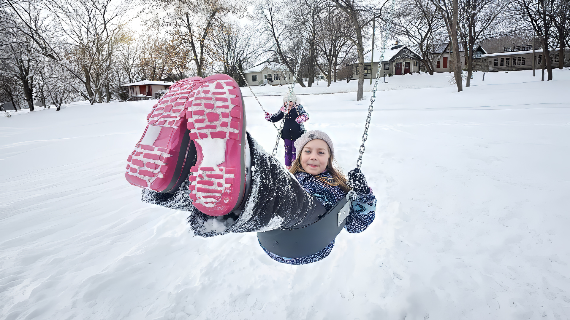two happy girls swinging on a snowy playground