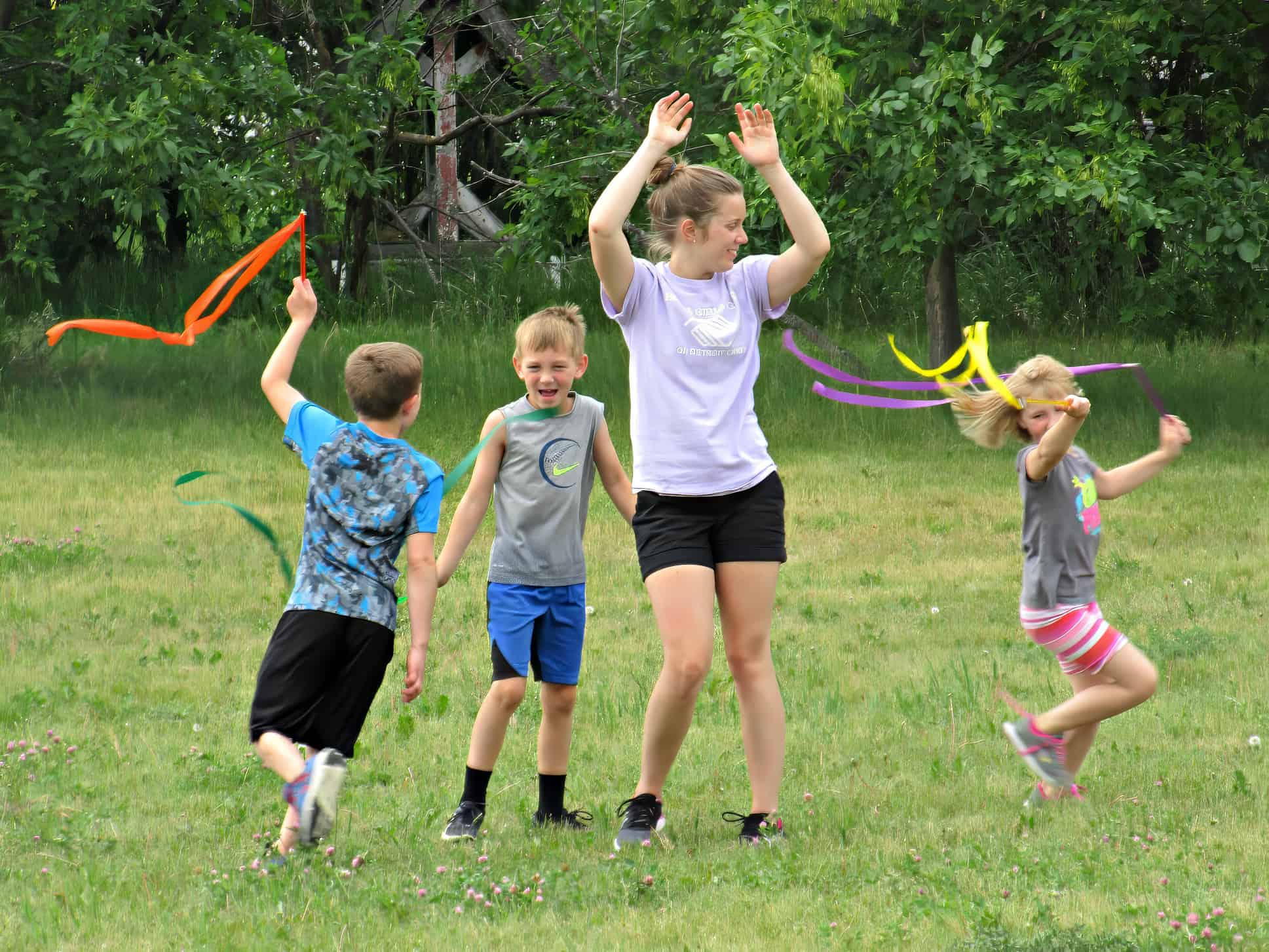 kids holding ribbons running around a staff member on the grounds