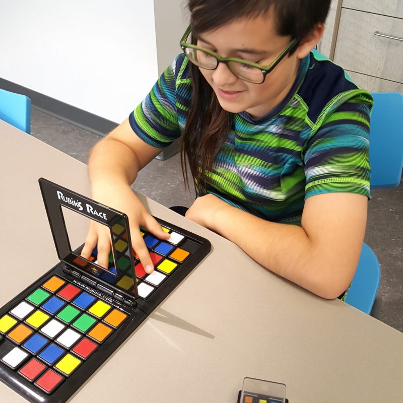school aged boy playing with Rubix puzzle