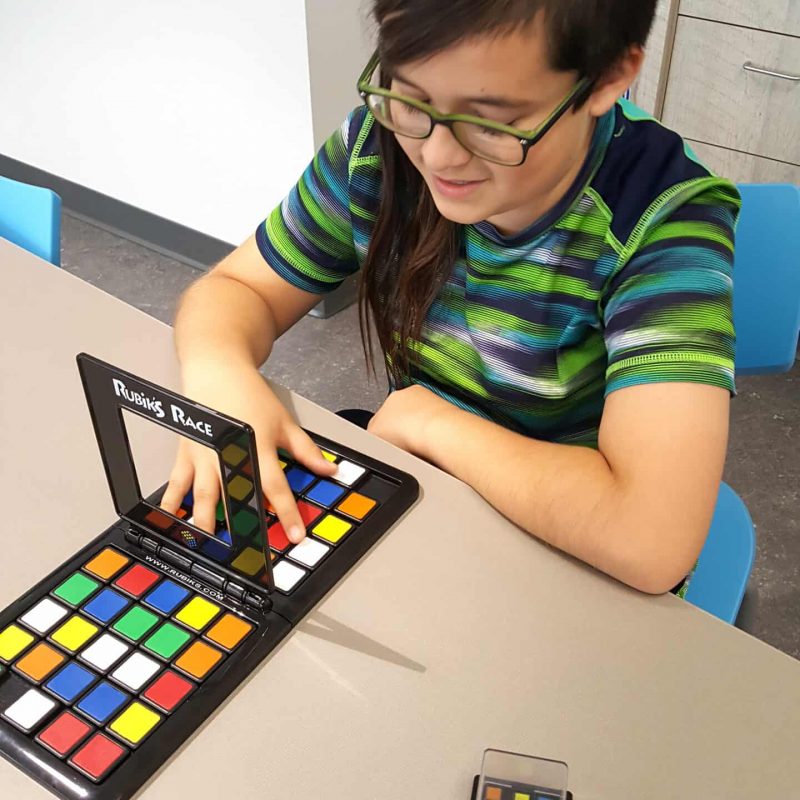 school aged boy playing with Rubix puzzle