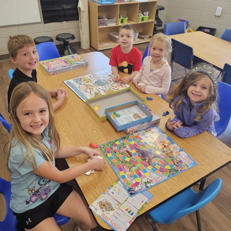 kids playing the Candy Land game seated at a table.